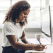 Woman happily taking notes with computer open next to her