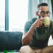 Man sitting drinking coffee and looking at phone